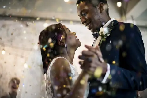 Close-up of a couple dancing cheek to cheek with confetti in the air